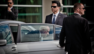 Dignitary Protection Services staff standing around male getting out of car